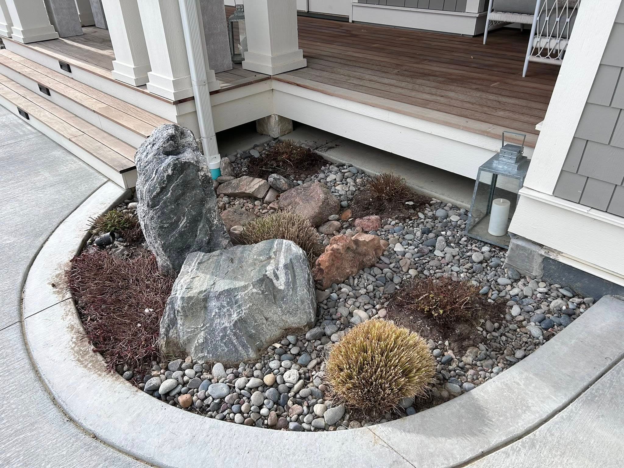 Curved concrete edge with river rocks and ornamental grasses