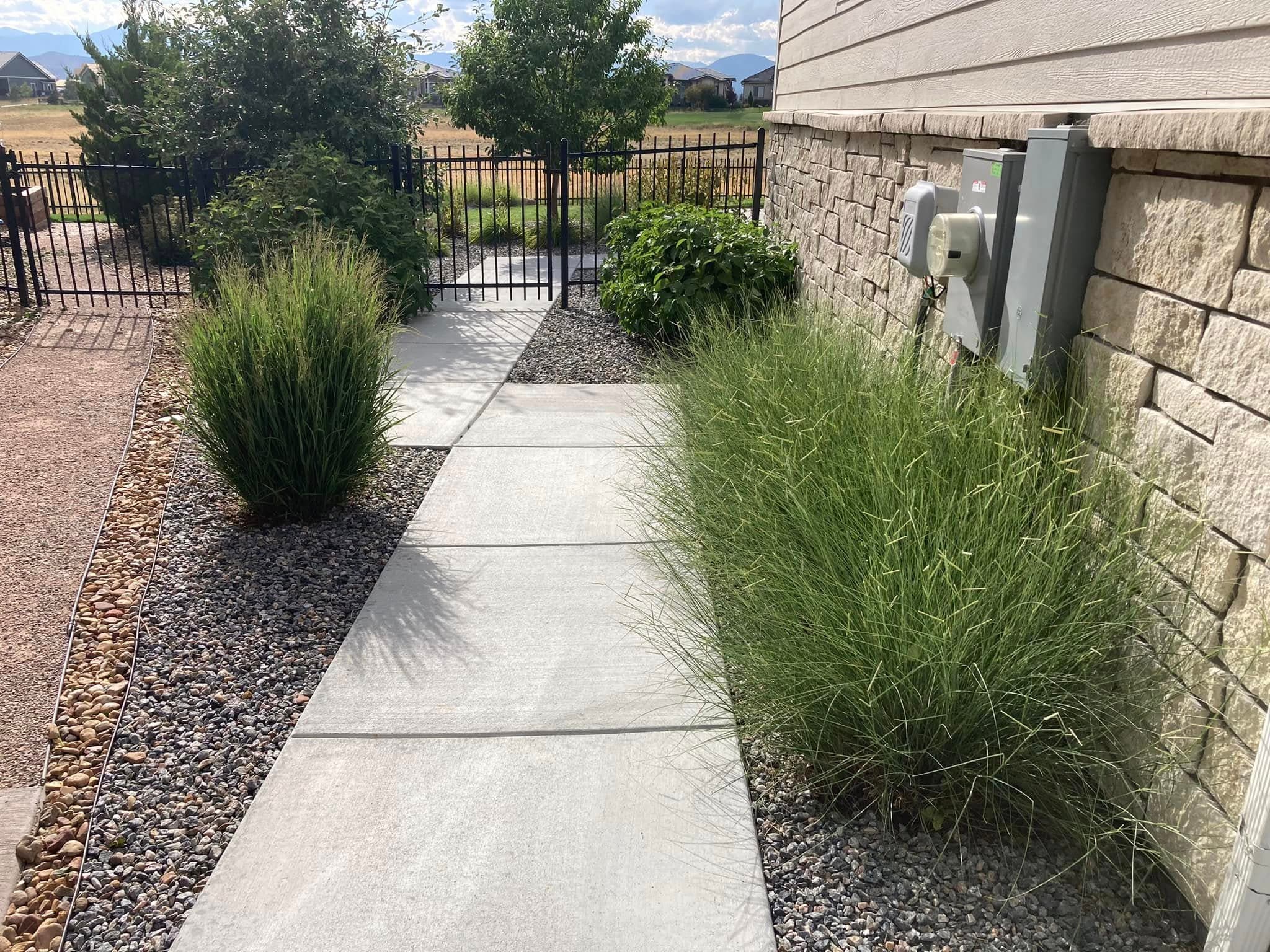 Entry pathway with gravel, ornamental grasses, and metal gate