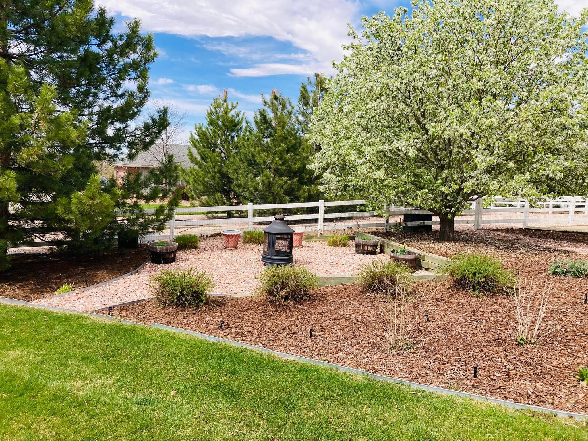 Landscaped yard with mature trees, gravel pathways, and seating