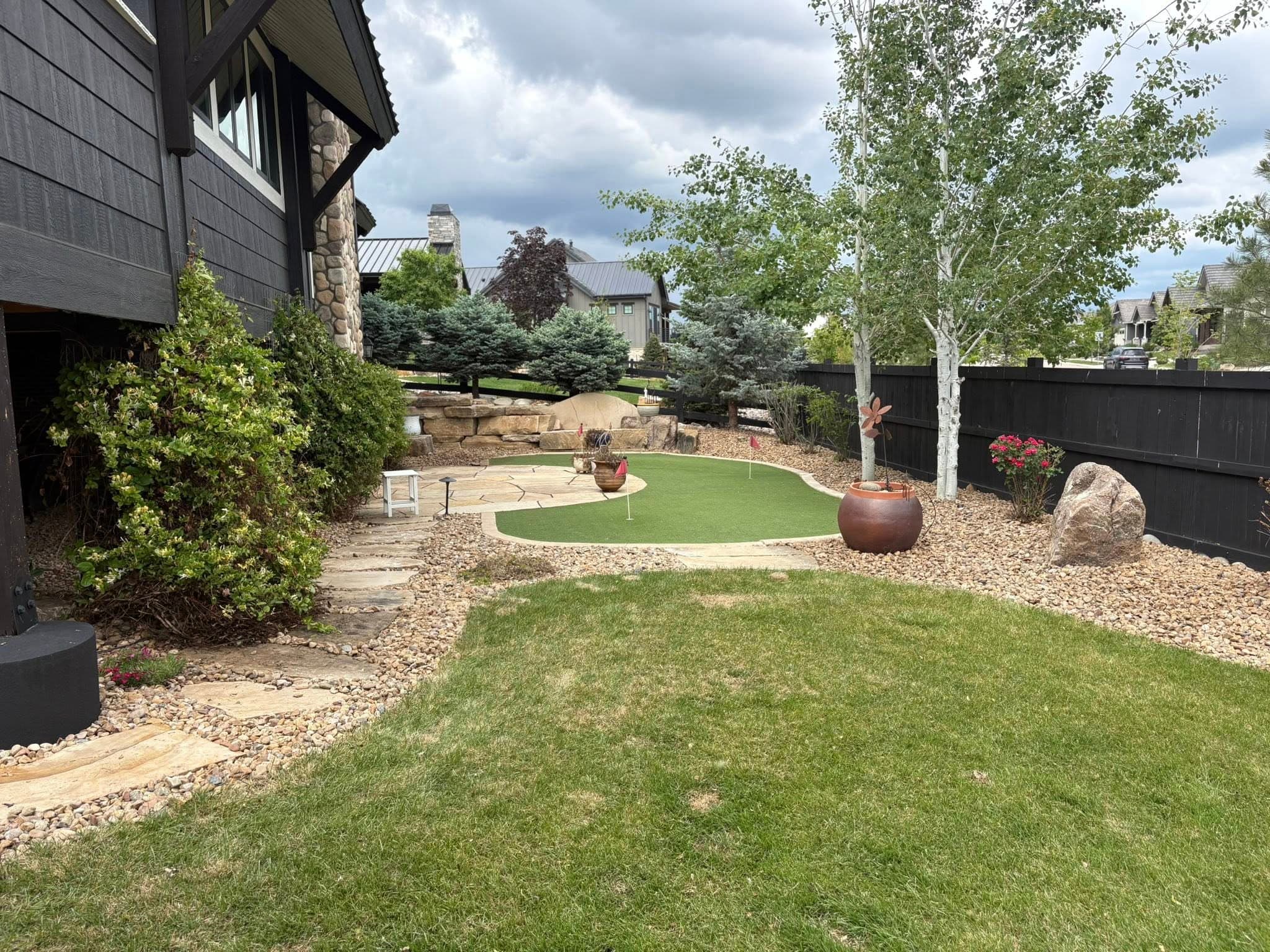 Backyard with manicured lawn and decorative boulders