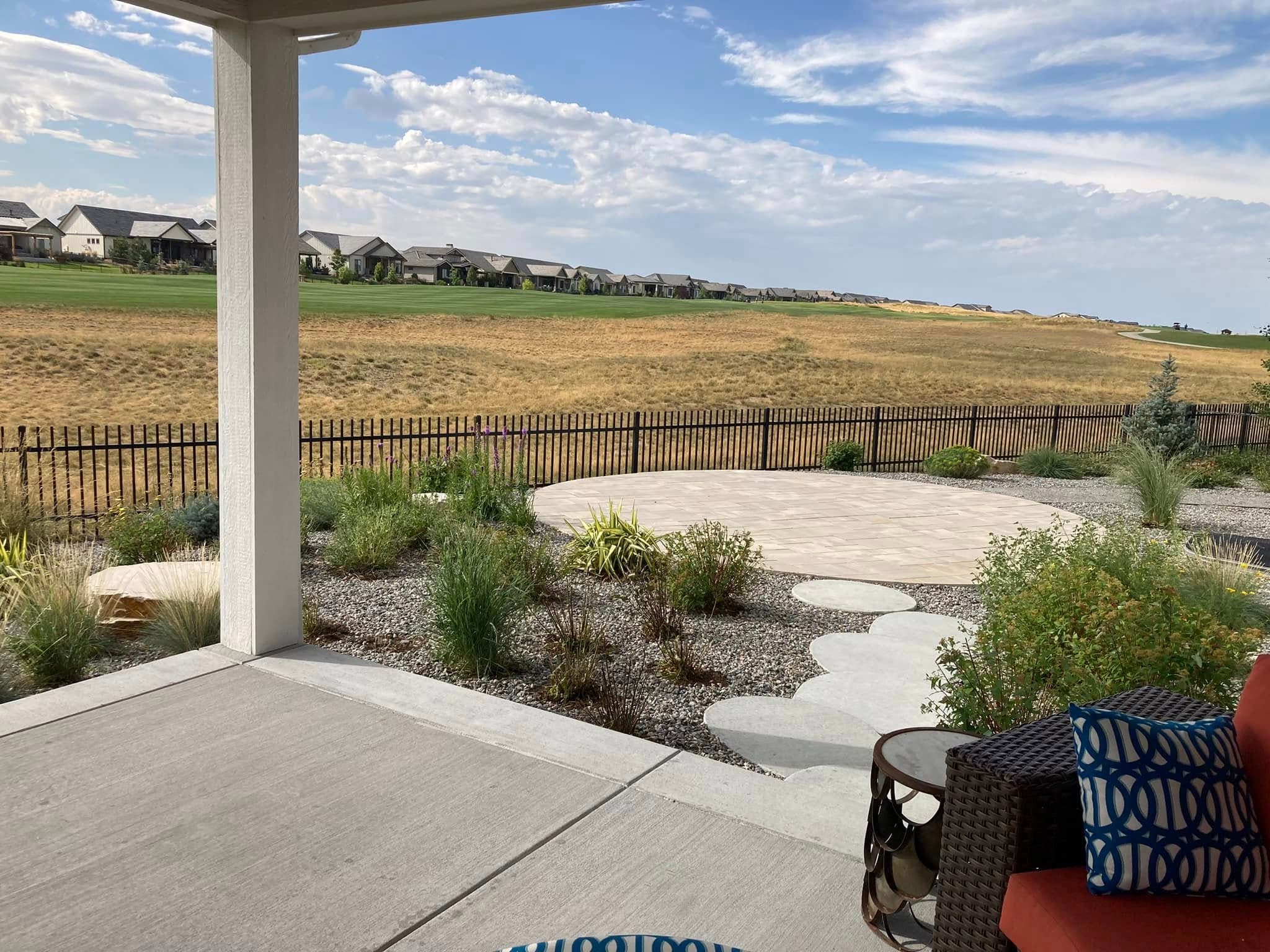 Covered patio overlooking landscaped yard with river rock and prairie plantings
