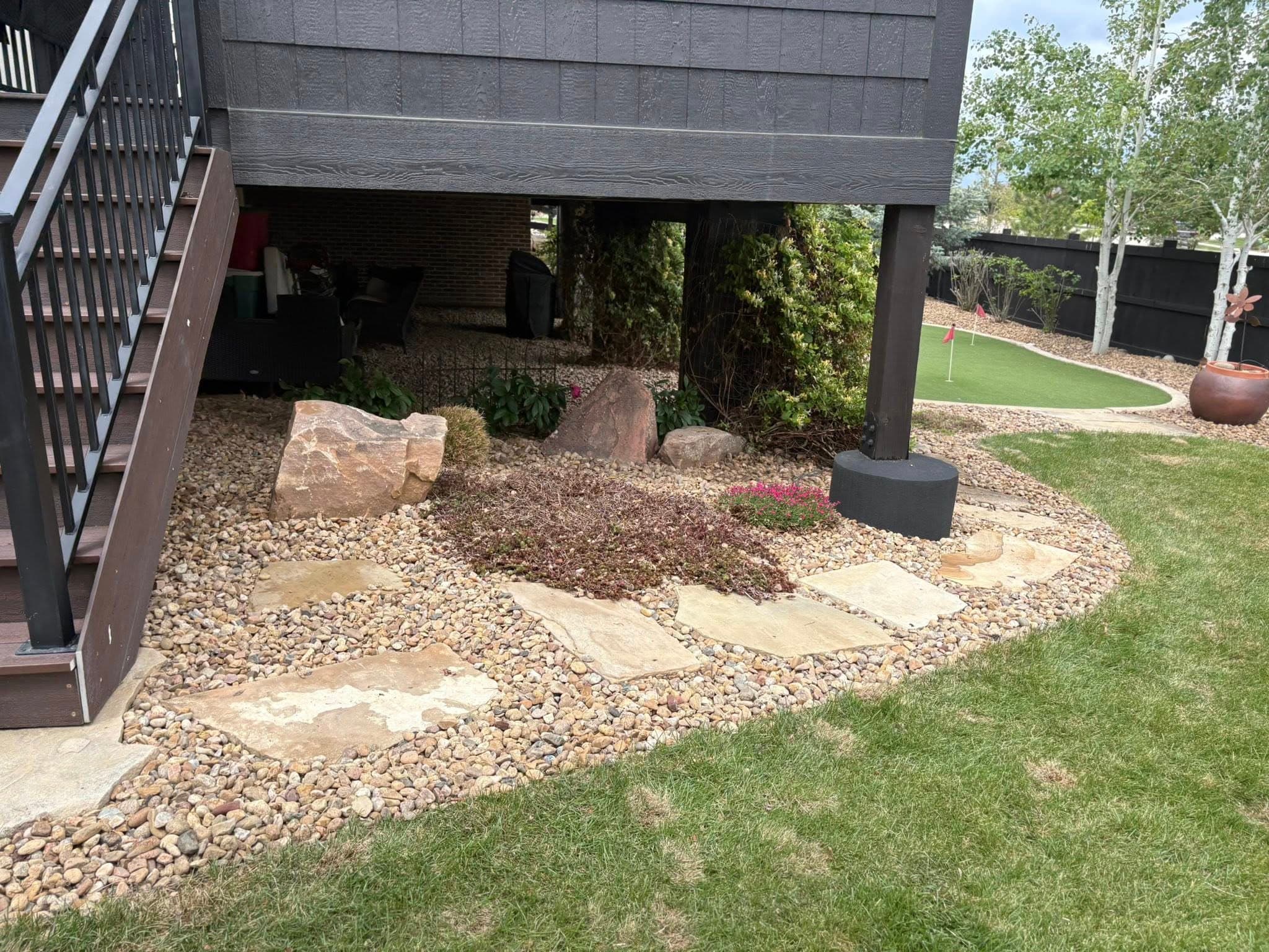Backyard with gravel pathways and decorative stones under deck
